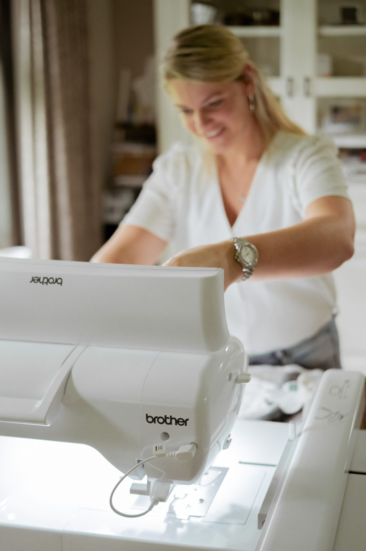 Vrouw in wit shirt werkt met Brother naaimachine aan tafel in lichte huiskamer